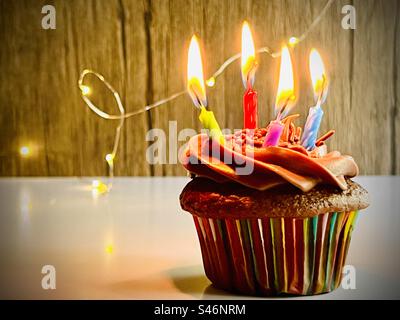 Cupcake al cioccolato con quattro candele di compleanno Foto Stock