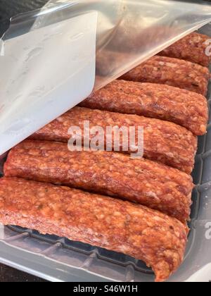 Kebab di kofte crudi di carne macinata in una confezione di plastica aperta dall'alto. Concetto di cibo non sano trattato. Foto Stock