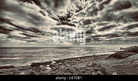 Spettacolari cieli sopra la costa di Northumberland - vedute di Craster in lontananza, catturate dalla costa che conduce al castello di Dunstanburgh. (Bianco e nero) Foto Stock