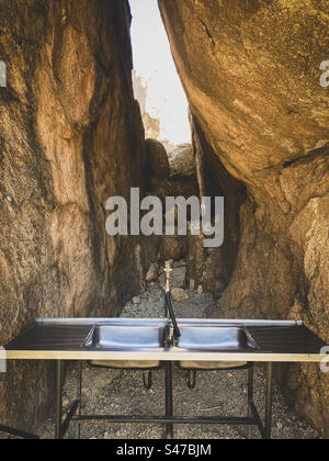 Un lavandino da cucina in acciaio inox tra grandi rocce in un campeggio in Namibia Foto Stock