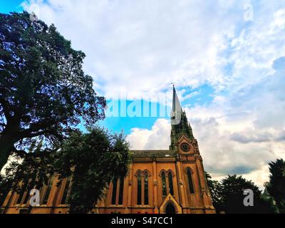 St Chiesa Margherita di Antiochia, architettura gotica e vittoriana di Brown. Prospettiva con albero nel cimitero. Foto Stock