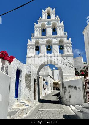 Il tradizionale villaggio non affollato di Megalochori a Santorini con il suo bellissimo campanile su uno stretto ciottolo in un giorno d'estate. Foto Stock