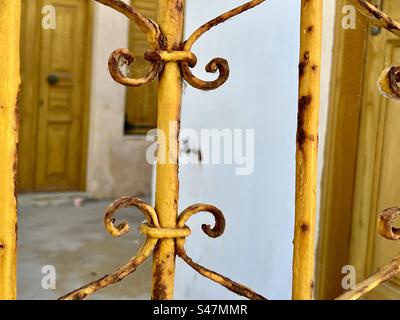 Un vecchio ma vibrante cancello di ferro dipinto di giallo a Oia. Foto Stock