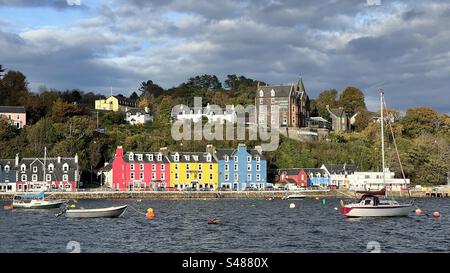 Immagine del Porto di Tobermory e dei tipici edifici colorati presi dal mare, con alcune piccole barche davanti all'immagine. Cielo blu. Foto Stock