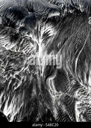 Primo piano sulla sabbia in spiaggia con motivi creati dall'azione mareale Foto Stock