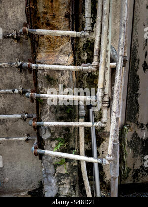 Infrastrutture idrauliche obsolete nel vicolo dietro l'edificio in una città densa Foto Stock