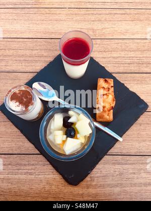 Piatto di dessert in un ristorante, su un piatto di pietra quadrata nera su un tavolo di legno. Foto Stock