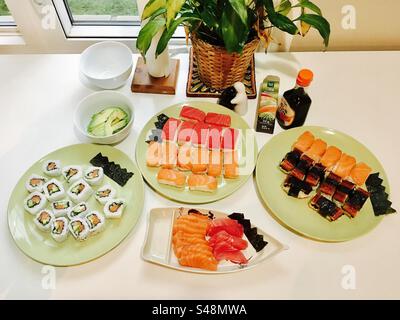 Una collezione di piatti di sushi fatti in casa su un tavolo da cucina Foto Stock