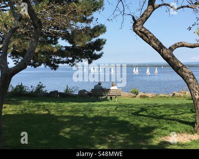 Foto di un paesaggio pittoresco di una coppia seduta su una panchina del parco di fronte al fiume a Ottawa, Ontario, Canada Foto Stock