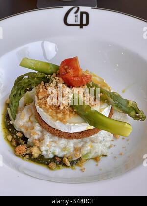 Primo piano di un risotto gastronomico ricostruito con riso bianco, asparagi, crumble, peperoni su un piatto profondo del ristorante in un ristorante francese a Montpellier, Francia Foto Stock