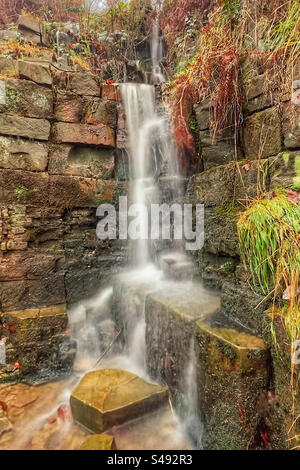 Piccola cascata a Rivington vicino a Chorley nel Lancashire. Cascata artificiale al parco a leva con acqua sfocata che mostra movimento. Foto Stock