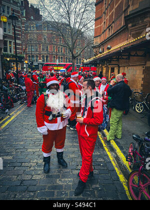 Uomini vestiti con abiti da Babbo Natale che parlano e fanno una pausa nel centro di Londra, Inghilterra, Regno Unito Foto Stock