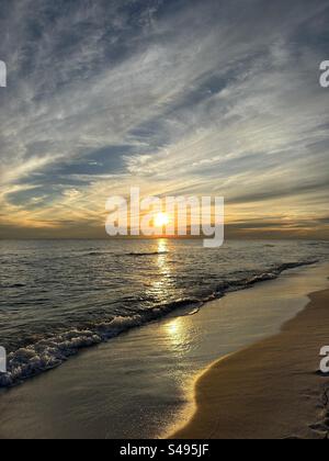 Sole dorato con nuvole che tramontano sulle acque del Golfo del Messico a Miramar Beach in Florida Foto Stock