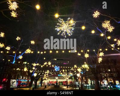 Luci invernali a Sloane Square a Chelsea, Londra. Stelle e lampade a corda sugli alberi. Visto a Natale di notte. Foto Stock