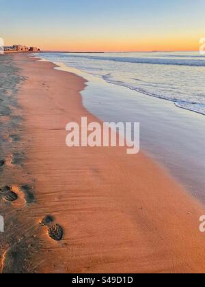 Bella luce di mattina presto nelle tonalità rosa e arancio su una spiaggia di sabbia vuota a Burriano, vicino a Castellon in Spagna. Il momento dell'alba all'inizio di gennaio 2024. Foto Stock