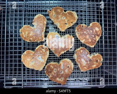 Torte tradizionali gallesi fatte in casa a forma di cuori rinfrescanti sulla griglia per torte. Foto Stock