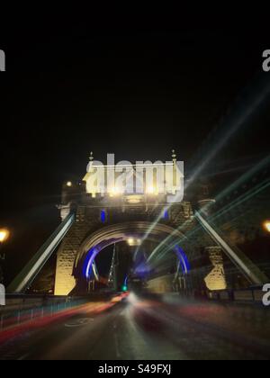 Il traffico passava lungo la strada del Tower Bridge, attraversando il Tamigi di notte Foto Stock