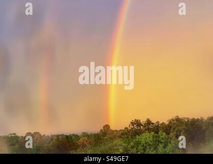 Doppio arcobaleno nel cielo del tramonto dopo la tempesta visto attraverso il vetro bagnato della finestra. Natura panoramica. Orizzontale. Cielo drammatico. Foto Stock