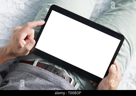 Close up di un giovane uomo di sollevamento sinistra dito indice oltre lo schermo bianco di una tavoletta digitale. Persona inizia a lavorare sul tablet a casa. Uomo sdraiato ho Foto Stock