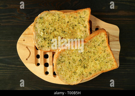 Coppia di burro all'Aglio toast sulla piastra in legno servito su Dark colore di sfondo Foto Stock