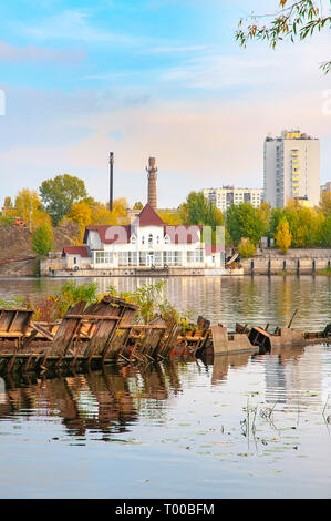 Scatafascio barca sul fiume Dnieper a Kiev, in Ucraina, in autunno. In background, ypou può vedere un disabitata casa galleggiante. Nuvole di luce galleggiante in una Foto Stock