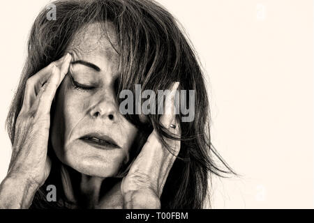 Immagine in bianco e nero di una donna matura tenendo le mani sulla testa del dolore. Foto Stock
