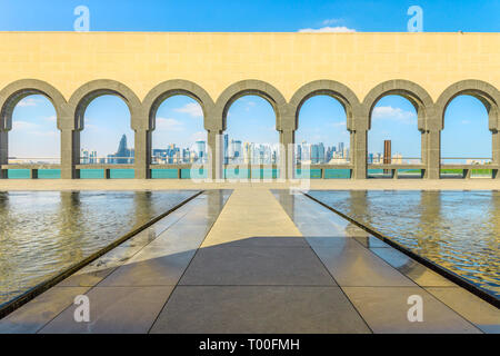Doha West Bay skyline attraverso la serie di arcate rivestite lungo le caratteristiche di acqua in una giornata di sole. Popolare attrazione turistica nella città di Doha lungomare, in Qatar Foto Stock
