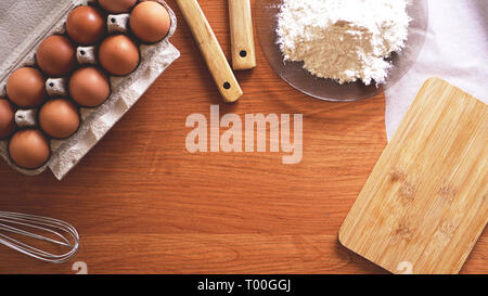Ingredienti e utensili per la cottura su un pastello sullo sfondo di legno, vista dall'alto. Concetto di cucina, e Pasqua Foto Stock