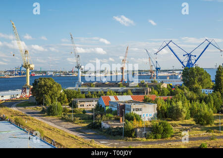 Magazzini e dock con giallo, blu e arancione Gantry cranes, porto di Warnemunde, Germania, Europa Foto Stock