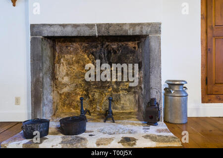 Caminetto in pietra con profilo in pietra tagliata, finitura in ghisa e pentole in ghisa nera in cucina all'interno di una vecchia casa del 1760 circa. Foto Stock