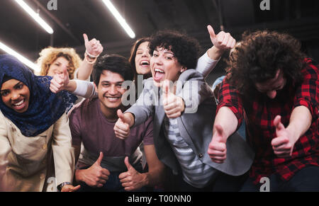 Ritratto di giovane eccitato multiethnics business team di sviluppatori di software in piedi e guardando la fotocamera mentre si celebra il successo all'avvio moderno Foto Stock
