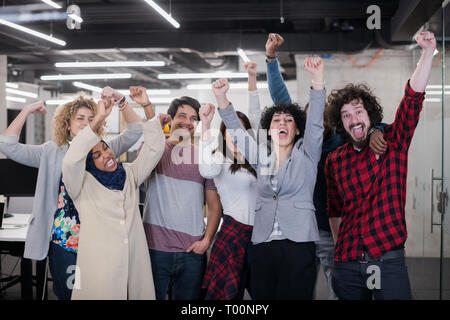 Ritratto di giovane eccitato multiethnics business team di sviluppatori di software in piedi e guardando la fotocamera mentre si celebra il successo all'avvio moderno Foto Stock