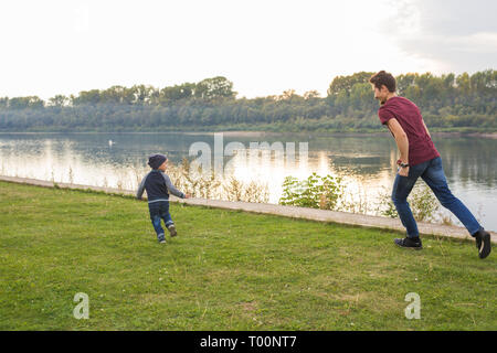 Genitori e figli concetto - Padre giocando con un piccolo figlio cercando di catturare lui Foto Stock