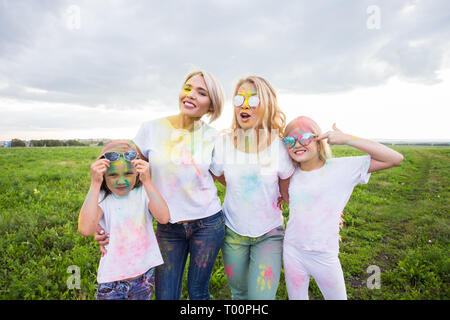 La famiglia, il festival di holi e concetto di vacanze - Ritratto di madri e figlie coperto di vernice Foto Stock