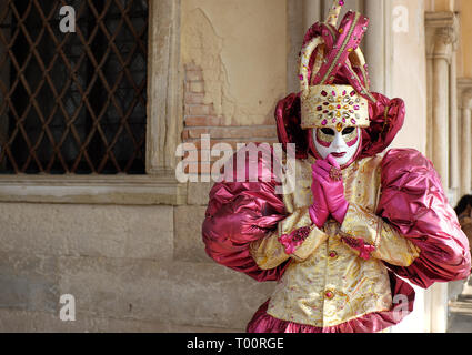 L'uomo vestito di tradizionale maschera e costume per il Carnevale di Venezia in piedi al palazzo ducale di Piazza San Marco, Venezia, Veneto, Italia Foto Stock