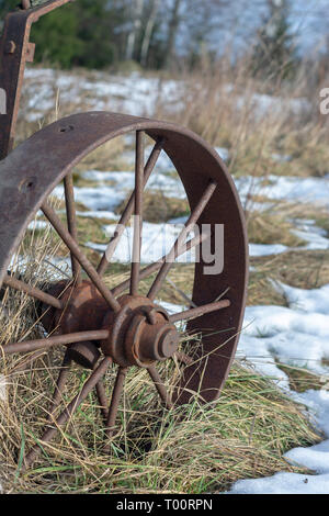 Vintage ruota in ferro su erba secca e neve closeup Foto Stock