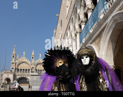 Giovane vestito in tradizionale maschera e costume per il Carnevale di Venezia in piedi in Piazza San Marco di fronte alla Basilica di San Marco, Venezia, Veneto, Ita Foto Stock