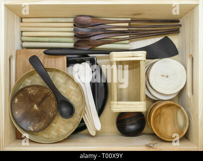 Set di vari in legno esotico stoviglie in una scatola di legno. Il set è costituito da noce di cocco, il bambù e il palm tree tazze, ciotole, cucchiai, spatole Foto Stock