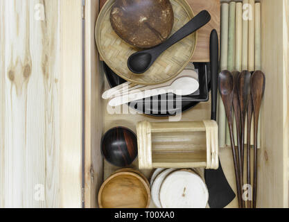 Set di vari in legno esotico stoviglie in una scatola di legno. Il set è costituito da noce di cocco, il bambù e il palm tree tazze, ciotole, cucchiai, spatole Foto Stock