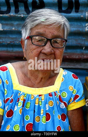 ANTIPOLO City, Filippine - 11 Marzo 2019: una matura donna filippina si appoggia su un marciapiede e pone per la fotocamera. Foto Stock