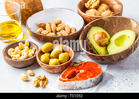 Selezione di grassi sani fonti: pesce, noci, olio di olive, avocado su sfondo bianco. Foto Stock