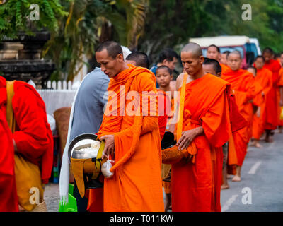 I monaci buddisti in arancione vesti coda per mattina alms dando cerimonia, Luang Prabang, Laos Foto Stock