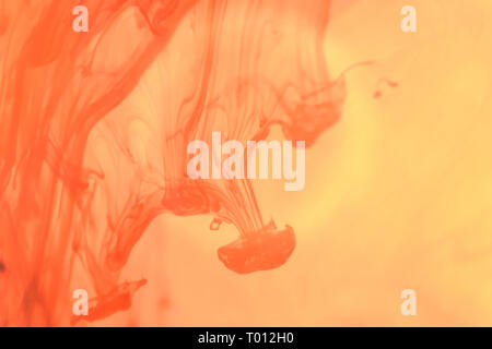 Inchiostro arancione scende in acqua. Fantasia di liquido schizzi d'arte. Abstract Background. Foto Stock