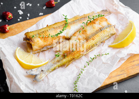 Due smelleds pesce a cuocere la carta con il limone Foto Stock