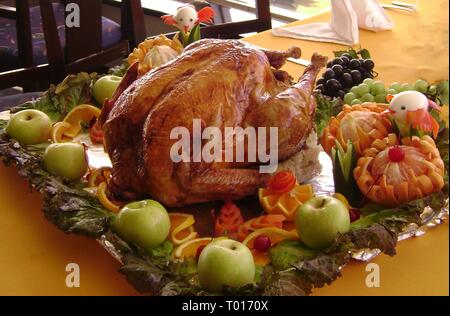 Tutto il tacchino arrosto servita su un letto di foglie di lattuga, mature pomeli, mela verde, uva e arance fette Foto Stock