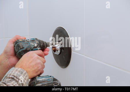 Installazione di un nuovo sulla doccia rubinetto miscelatore in un bagno nella vasca da bagno di calore di controllo Foto Stock