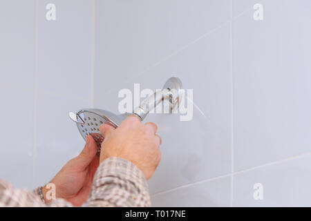 Workman riparazione di testa di doccia nella stanza da bagno gocce di acqua sulla doccia Foto Stock