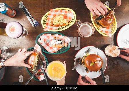 Pranzo al pub con gli amici, hamburger, hot dog, birre e cocktail Foto Stock