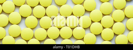 Piccole pillole di colore giallo su sfondo bianco di close-up Foto Stock