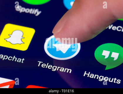 Dito che preme una icona di collegamento per caricare il telegramma app su un tablet o smartphone touchscreen. Pulsante di telegramma. Foto Stock